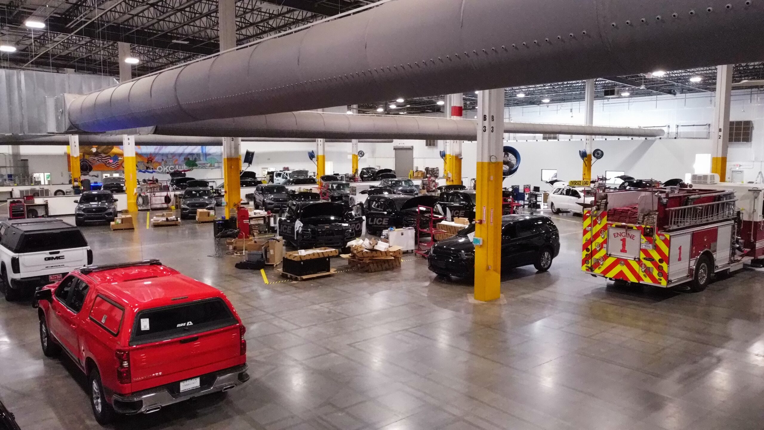 Emergency vehicles being professionally upfitted inside a specialized vehicle installation facility