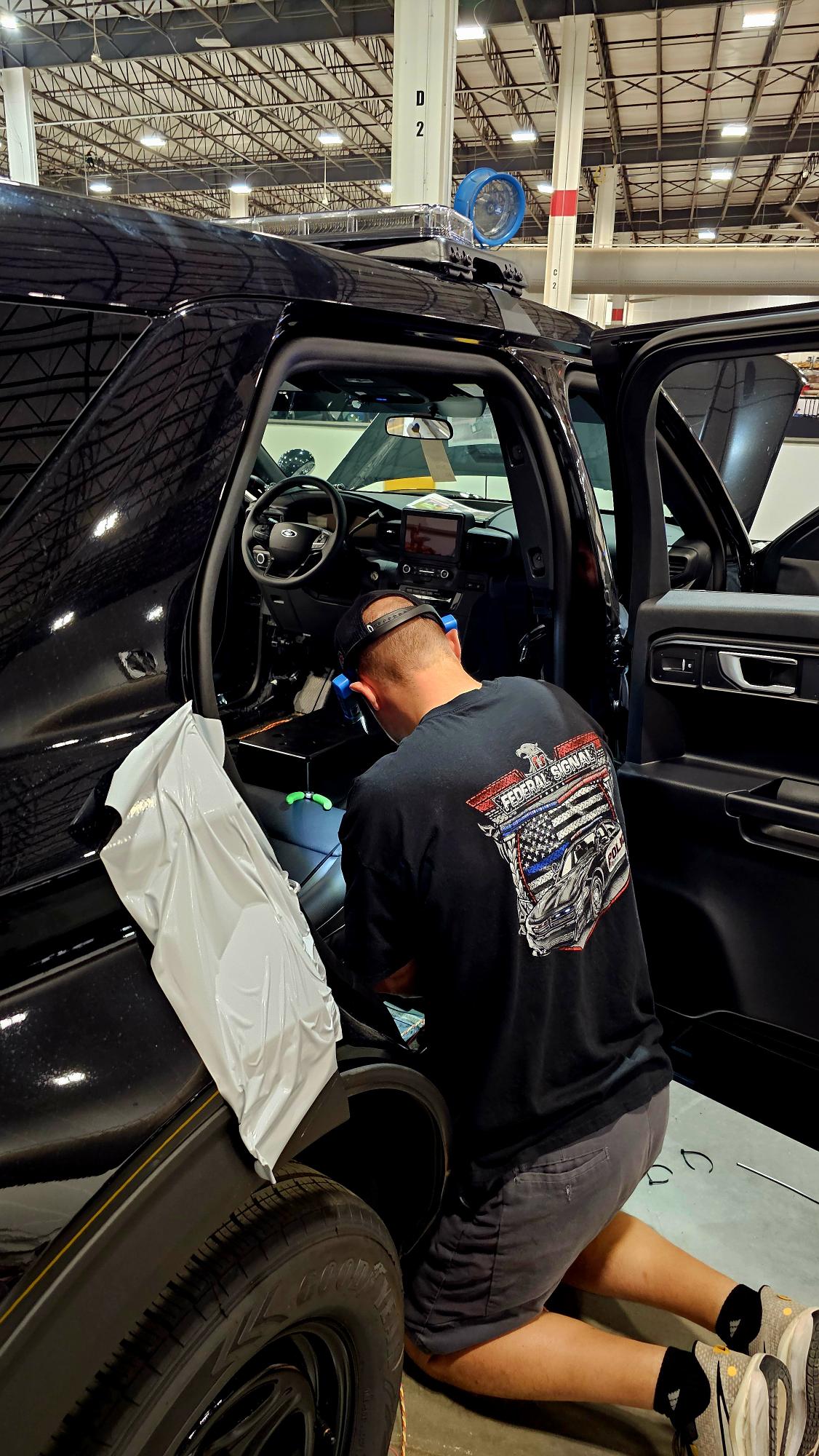 Technician installing emergency electronics and wiring inside a vehicle
